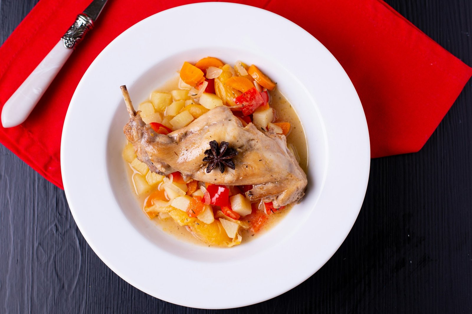 Baked rabbit with vegetables on a white plate, restaurant dish on the table